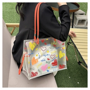 Close-up of a transparent PVC tote bag with colorful heart prints and orange handles