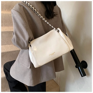 Close-up of white patent leather flap bag with black and white woven chain strap
