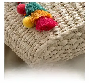 Detailed macro view of woven straw bag texture with colorful bohemian tassels and pom-poms