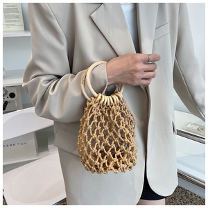 Detail of handmade woven straw bag with dual round wooden handles and hollow mesh pattern