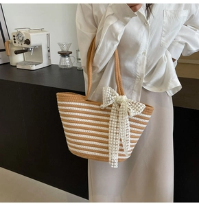 Detail of striped woven tote bag with lace bow and pearl accent on casual summer beach purse