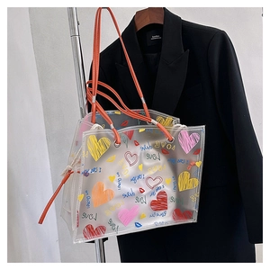 Close-up of transparent PVC tote bag with colorful hand-drawn heart prints and orange handles