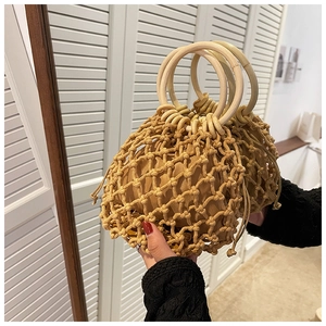 Detail of handmade hollow woven straw bag featuring round wooden handles and fabric liner