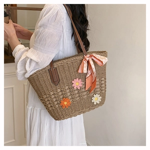 Dettaglio borsa in paglia con fiori all'uncinetto e nastro foulard colorato