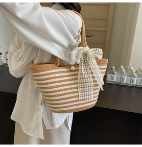 Detail of striped woven beach bag with large white lace bow and pearl buckle closure