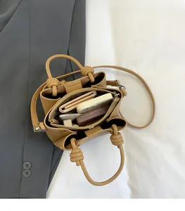 Internal view of a tan leather crossbody bag showing spacious compartments with essentials