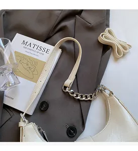 Detail of off-white crescent bag with pebble texture and silver chain strap on a blazer