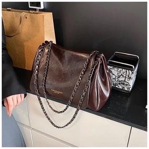 Detail of dark brown glossy leather texture and gold lettering on flap chain bag