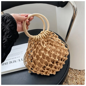 Close-up of handmade woven straw bag featuring round wooden handles and drawstring pouch