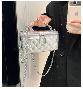 Detail of silver quilted chain bag with adjustable metal ball buckle and top handle