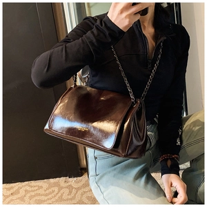 Detailed view of glossy dark brown leather shoulder bag with vintage chain strap