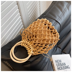Detail view of hollow hand-woven straw bag with large circular wooden handles and drawstring