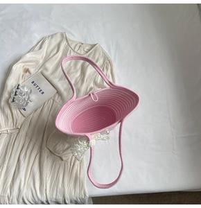 Detailed top view of pink and white striped woven straw bag with lace bow and pearl charm