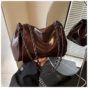 Close-up of glossy dark brown tote bag with metal chain strap and soft pleated texture