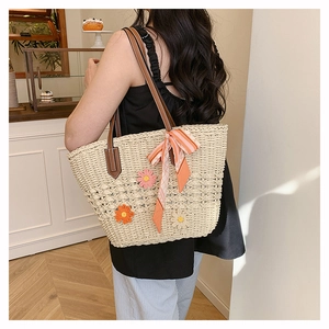 Dettaglio della borsa tote intrecciata con fiori in maglia, manici in pelle e foulard