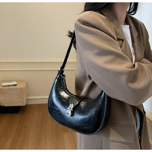 Detail of black glossy hobo bag featuring crinkled patent leather and silver metal buckle