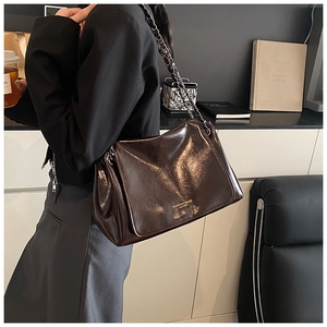 Detail view of dark chocolate oil wax leather crossbody bag with metallic chain strap