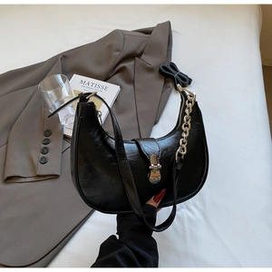 Detail of black PU leather half-moon bag with bold silver chain and metallic buckle