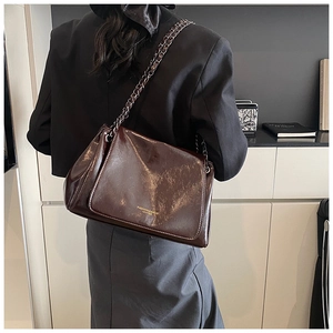 Detail view of dark brown oil wax leather texture and gold embossed fashion lettering