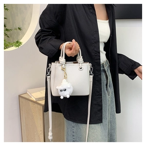 Detail of white lychee leather bag featuring a rope knot handle and plush lamb charm
