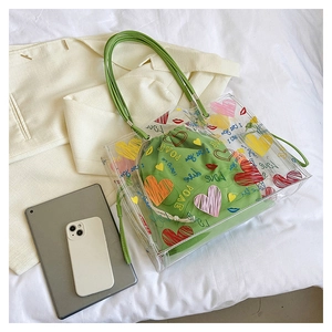 Detail of transparent PVC tote bag with green drawstring pouch and colorful heart prints
