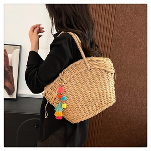 Macro shot of hand-woven straw tote bag with colorful pom pom tassel and rope handles