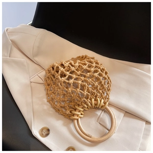 Detail of hand-woven straw bag with round wooden handles on a beige blazer