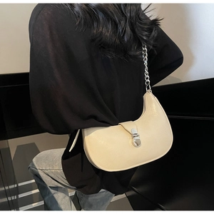 Détail du sac demi-lune crème avec bandoulière chaîne argentée et fermoir métallique à l'épaule