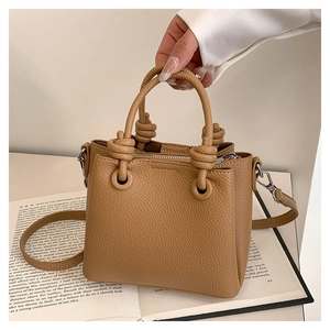 Detail of camel lychee pattern leather handbag with unique knotted handle and strap