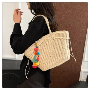 Detail of cream woven tote bag with colorful tassel pom-poms and drawstring closure