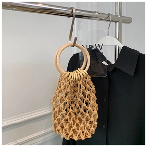 Detailed macro view of beige handmade woven bag with large round wooden handles