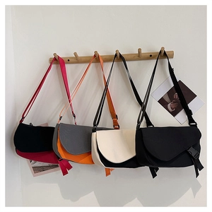 Detail view of four trendy contrast-color crossbody bags hanging on wooden wall hooks