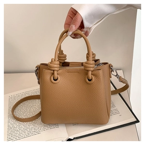 Detail of tan pebble leather mini bag with knotted handle and metal zipper closure