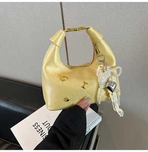 Detail of yellow metallic hobo bag with gold bear charm and pearl lace bow accents