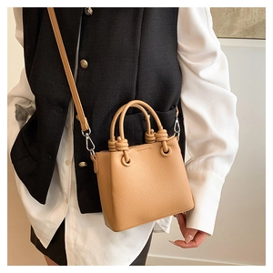 Detail of light beige pebble leather handbag with knot handle and silver metal hardware