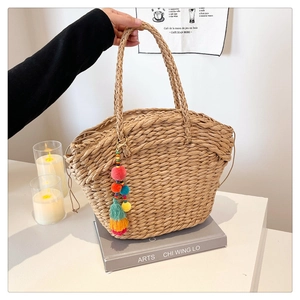 Detailed close-up of woven straw handbag texture featuring a colorful tassel pendant charm