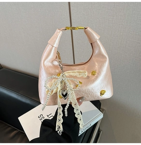 Detail of pink hobo bag with lace bow, pearl accents and golden heart pendant