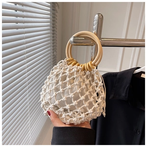 Detail of hand-woven white crochet bag featuring wooden circular handles and inner drawstring