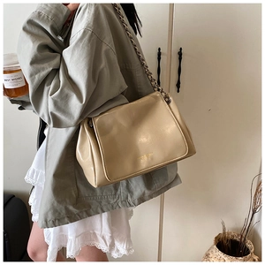Detail of beige glossy leather handbag featuring vintage bronze chain and elegant flap closure