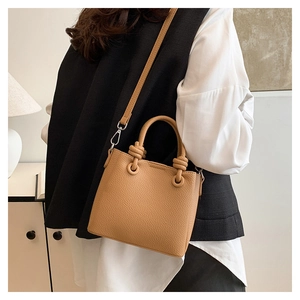 Detail of tan pebble leather mini bag with knot handle and silver hardware strap