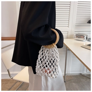 Detail of hand-woven white cotton net bag with round wooden handle held by a model