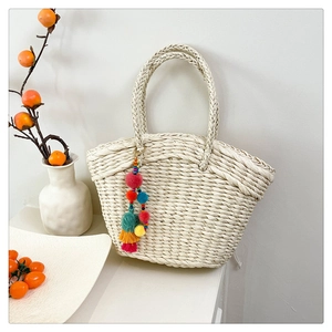 Detailed woven pattern of off-white basket bag with colorful pompom charm tassel