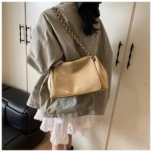 Detail of champagne gold chain bag with woven leather strap and textured glossy finish