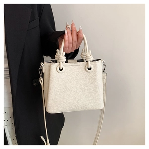 Close-up of cream lychee texture leather handbag with unique knotted handle and strap