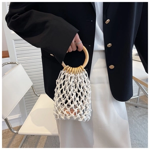 Detail of white crochet handbag with circular wood handles and beaded embellishments