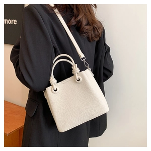 Detailed macro view of white lychee pattern leather handbag with metallic strap hooks