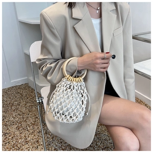 Detail of hand-woven bucket bag with wooden circular handles and drawstring liner
