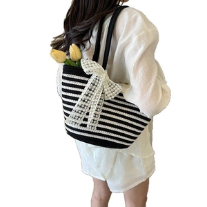 Large striped woven beach bag featuring white lace bow and elegant top handles