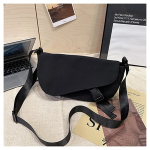 Detail of black canvas messenger bag featuring a secure buckle closure and nylon strap