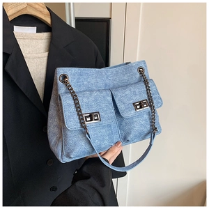 Detail of light blue denim chain bag with quilted patterns and double front lock pockets